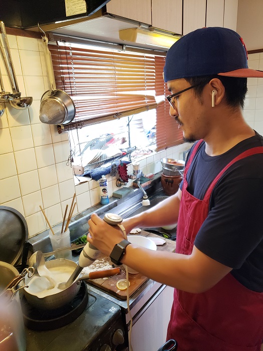 「nakamuLab.」店主の中村隆志さん。手鍋に張った鶏白湯スープにブレンダーをかけ、しっかりと乳化。細かい気泡ができる