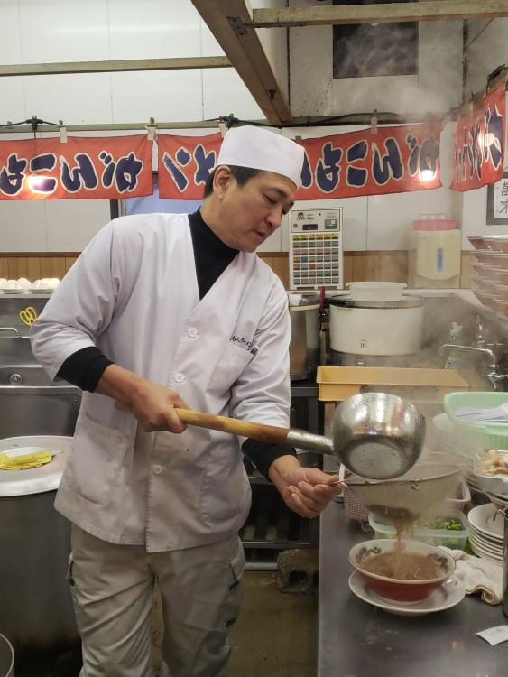 「がんこもんラーメン」店主の入江宏治さん。10代後半でラーメンの道に入り、30年以上豚骨ひと筋。カンカンッ！と網を叩きながらスープを濾す