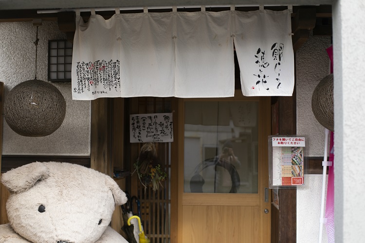 糸島市高田の裏通り。白い暖簾と大きなぬいぐるみが目印